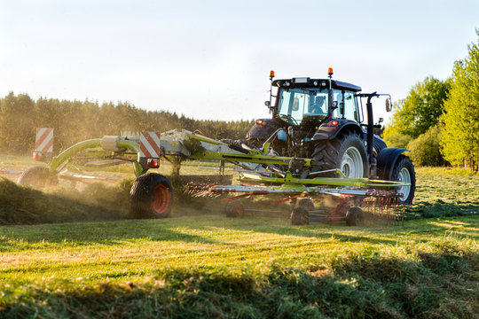 Tractor with hay tedder on field
