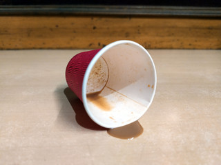 a red color paper tea cup some tea coming out from tea cup