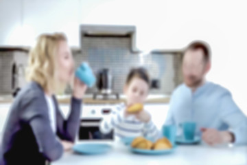 Blur photo - abstract image for the background. Young family with a child having dinner in the kitchen.