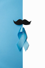 Light blue ribbon with mustache on white and blue background. Prostate Cancer Awareness, Movember...