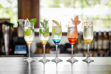 Colorful cocktails are lined up on the bar table.