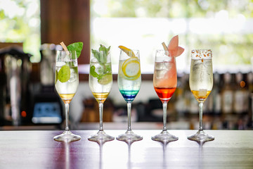 Colorful cocktails are lined up on the bar table.