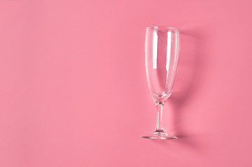Single empty glass for champagne lies on pink table on kitchen. Concept of celebrating. Space for text. Top view
