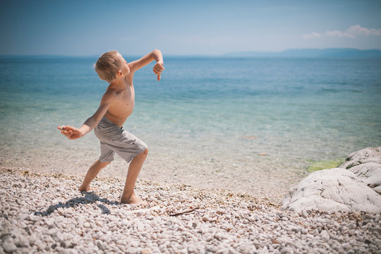 Boy throwing stones on beach