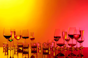 Set of various alcoholic beverages in glasses on a black reflective background.