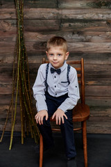 Loft style concept. Portrait of a cute boy of 10 years old sitting on a chair against the background of the interior in a room of wood.