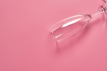 Single empty glass for champagne lies on pink table on kitchen. Concept of celebrating. Space for text