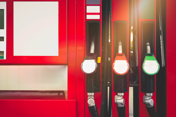 Fuel pump nozzles on red fuel dispenser in gasoline station with copy space.