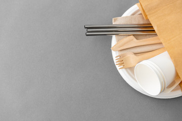 recycling and eco friendly concept - set of wooden forks, knives, paper cups and metallic straws...