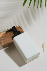 White shampoo bottle/ beauty product in tropical style with sea shell and wood. Beauty concept