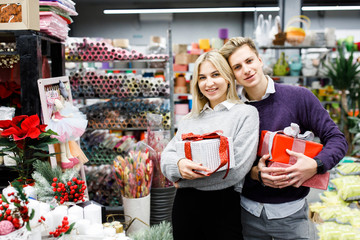 Portrait of young man with woman shopping presents in store in time before the winter holidays. Beautiful couple buys gifts for family and friends
