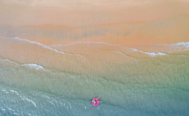 Aerial top view from drone, View of boy with swim ring in the sea and shade emerald blue water and wave foam at sunrise