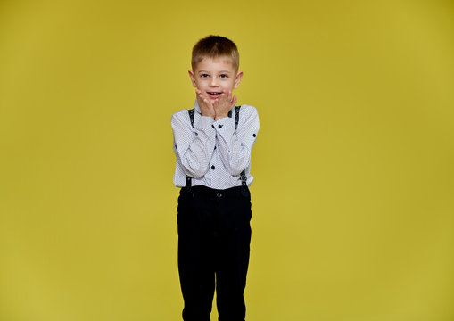 Portrait of a cute boy 10 years old schoolboy on a yellow background in trousers and a shirt. Standing right in front of the camera, Shows emotions, talks in different poses.