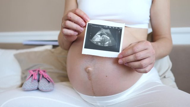 Pregnant Woman Holding Ultrasound Scan Photo On Belly