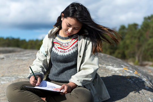 Teenage girl writing letter at seaside