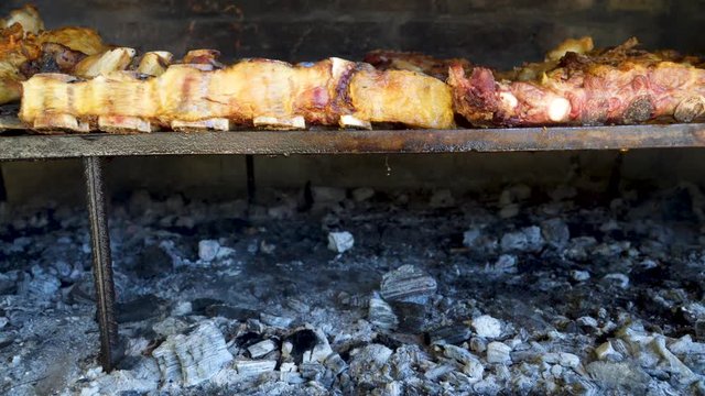 Lowering shot of traditional Argentinian asado revealing smoky hot embers