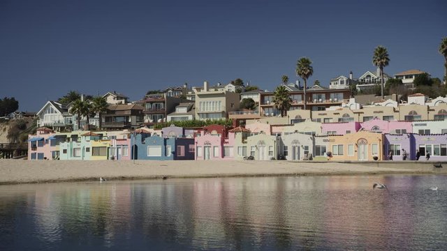 Panning shot of multicolor houses on beach / Capitola, California, United States