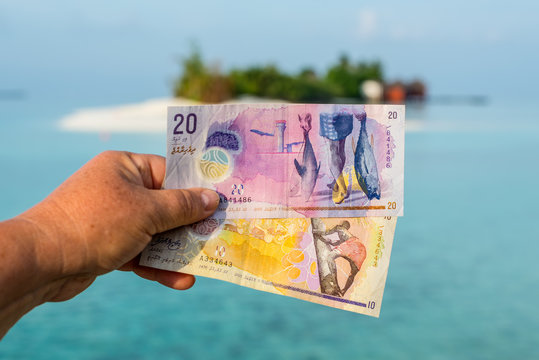 A tourist's show Maldivian rufiyaa bank note when she traveling in Maldives. Money of Maldives bank note in female's hand on the background of the island, salary incomes.
