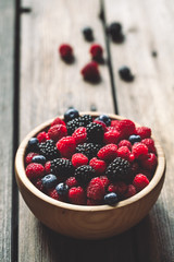 raspberries and blackberries on a wooden background in vintage style. Cutting board