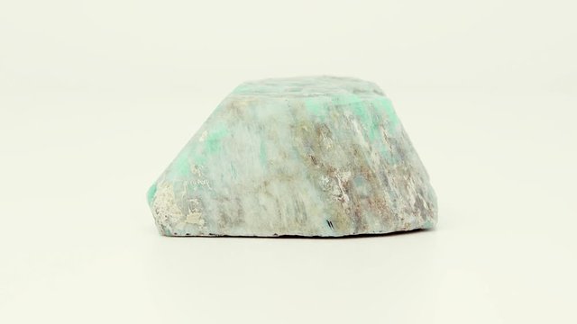 Extremely close view of roughly cut, green-blue Amazonite mineral chunk. Rotating completely. Looping