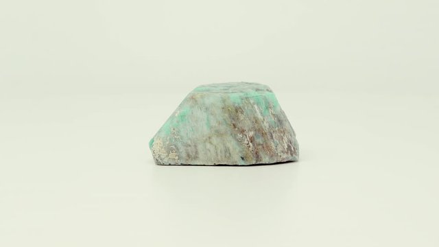 Close view of roughly cut, green-blue Amazonite mineral chunk. Rotating completely. Looping.