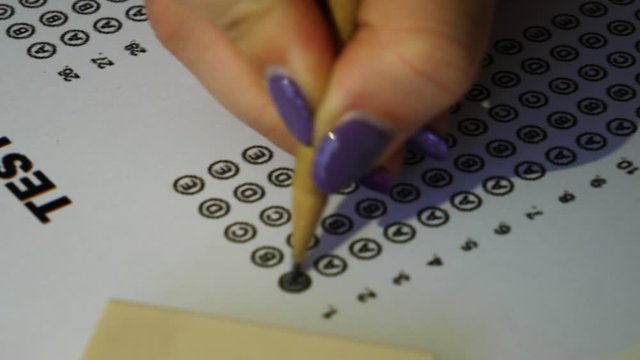 Female student checking test answer boxes with a pencil. Filling in answer sheet for test