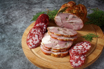 Smoked meat and salami on a cutting Board on a dark background