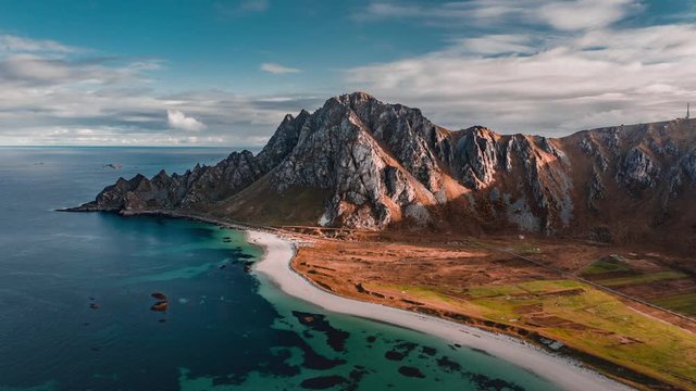 Aerial view of the magnificent Royken mountain on the island of Andoya, Norway. Transparent blue waters of the bay, white sandy beach, thin clouds above.
