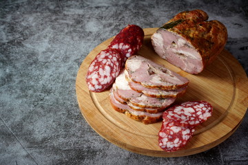 Smoked meat and salami on a cutting Board on a dark background