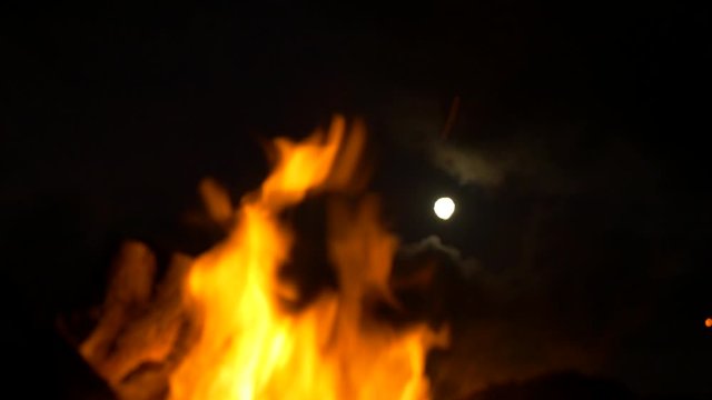 full moon reveal through bonfire embers and sparks in the air
