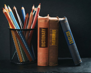 old books with pencils on stone shelf