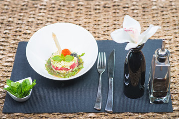 Classic traditional tartar salad laid in a round shape, stylish serving in an oriental style table in a restaurant.