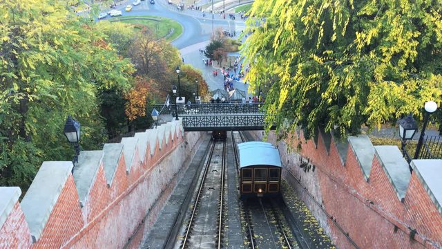 Tilt up shot of old historic funicular railway driving up to top of castle hill. Chain Bridge and Budapest in the background. Hungarian name is Budav&aacute;ri sikl&oacute;.