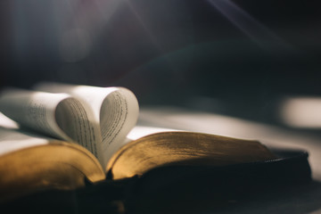 Soft focus open holy Bible at window,heart pages background