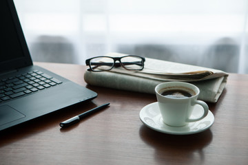 Newspaper with computer on table. Coffee break.
