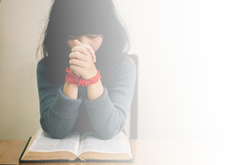 Woman holding the bible in hands and pray with copy space.