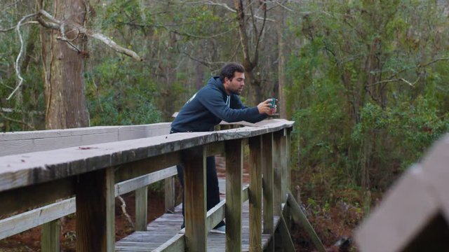 Man taking pictures video snapchat of nature trees swamp
