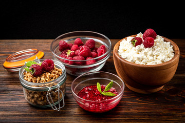 Cottage cheese, granola and fresh raspberry on dark wooden background.