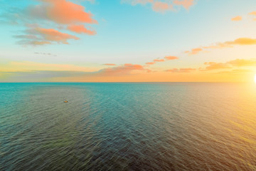 Vivid sunset over ocean with small boat - minimal aerial seascape