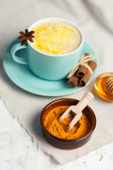 Golden Milk, turmeric latte made with curcuma, cinnamon, anise and honey. Healthy hot winter drink, natural and organic beverage. Close up, front view. Blue mug, neutral white background