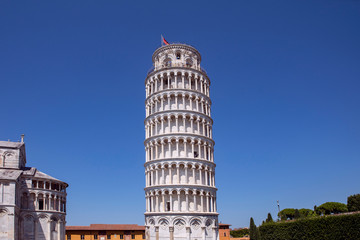 Leaning Tower of Pisa famous landmark with surrounding buildings on the square. Blue sky, summertime. Tuscany, Italy