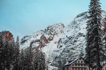 Fototapeta premium Italian alps in winter, mountains covered in snow during sunrise time, forest trees in winter.
