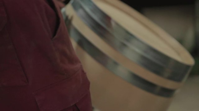 Cooper rolling away unfinished barrel, close up
