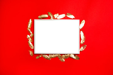 Creative vertical composition with white blank postcard template with gold leaves on red background.