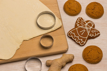 Fototapeta na wymiar Dough for baking ginger cookies on a cutting board, a form for cutting cookies, cookie blanks like a star and a circle.