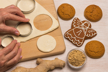 Dough for baking ginger cookies on a cutting board, cookie cutter, hands cut out cookies from the dough.