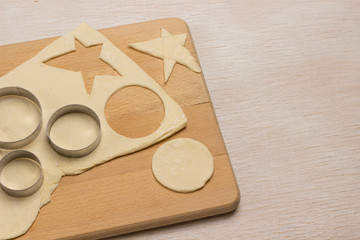 Dough for baking gingerbread cookies on a cutting board,  form for cookies cut blanks liver as a star and  circle .