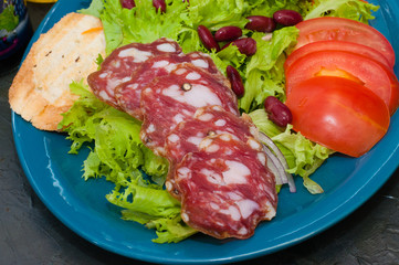 Salad with sausage, tomatoes, beans, carrots, spices, olive oil or sauce. Restaurant serving Italian food