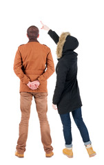 Back view of couple couple in winter jackets pointing.