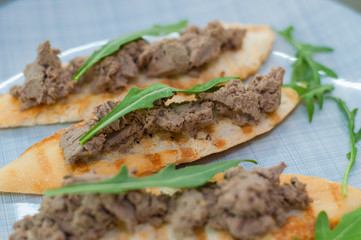 Croutons with paste and arugula. Festive appetizer, New Year's Italian dish. Side and top view, close-up